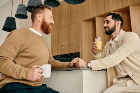 Dos hombres, una feliz pareja gay bebiendo jugo de naranja en una cocina moderna.