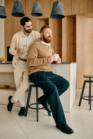 Two men enjoying a moment on stools in a kitchen of a modern apartment, deep in conversation.
