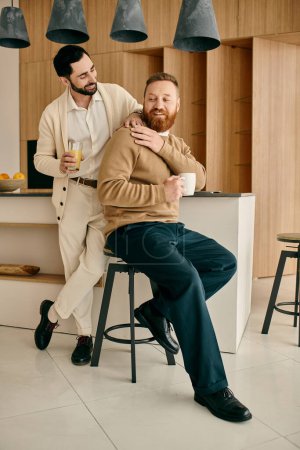 A man with a beard sits on a stool in a modern kitchen, sharing a tender moment with his partner.