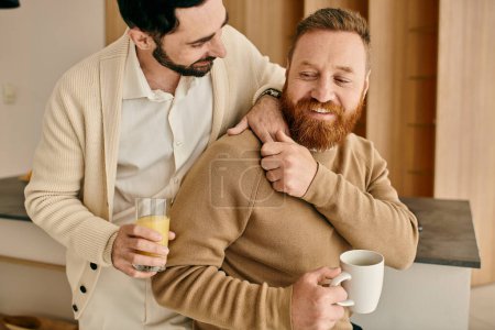 Photo for Two men, part of a happy gay couple, hug each other warmly in a modern kitchen, sharing a moment of love and connection. - Royalty Free Image