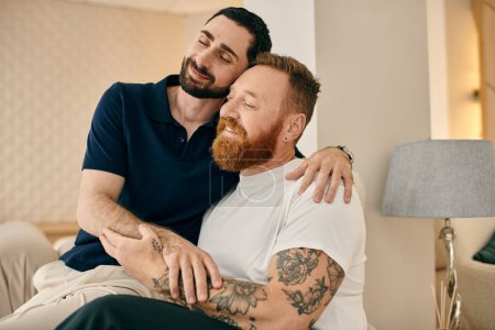 Téléchargez les photos : Deux hommes tatoués s'embrassent chaleureusement sur un canapé dans un salon moderne, partageant un moment d'amour et de connexion. - en image libre de droit