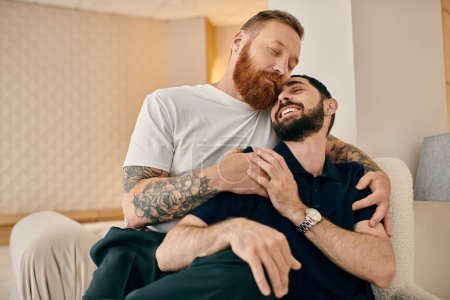 Téléchargez les photos : Deux hommes en vêtements décontractés s'embrassent chaleureusement sur un canapé confortable dans un salon moderne, exprimant leur affection l'un pour l'autre. - en image libre de droit