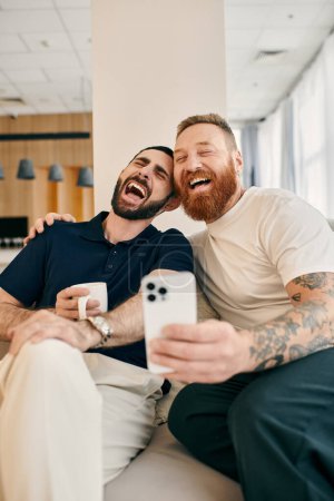 Two happy gay men, in casual attire, sit on a couch in a modern living room, sharing laughter and enjoying quality time together.