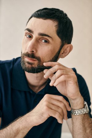 Un hombre en una pose pensativa, con una mano puesta en su barbilla, mostrando su actitud reflexiva e introspectiva.