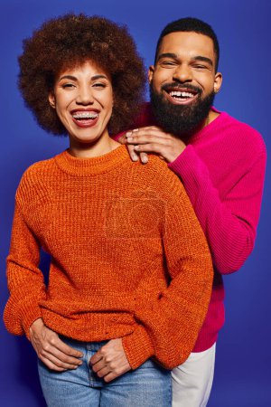 Photo for Young African American friends in vibrant casual attire stand together on a blue background, portraying the essence of friendship and unity. - Royalty Free Image