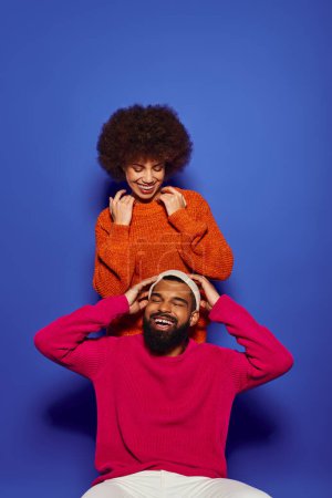 Photo for A young African American man sits on top of a womans head in vibrant casual attire, showcasing friendship. - Royalty Free Image