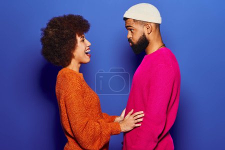 Téléchargez les photos : Un homme et une femme afro-américains, amis, se tiennent côte à côte dans une tenue décontractée dynamique sur un fond bleu. - en image libre de droit