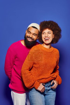 Foto de Un joven hombre y una mujer afroamericanos, vestidos con vibrantes atuendos casuales, están uno al lado del otro en una muestra de amistad. - Imagen libre de derechos