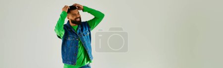 Photo for A man with a beard wearing a green long sleeve and blue jeans. - Royalty Free Image