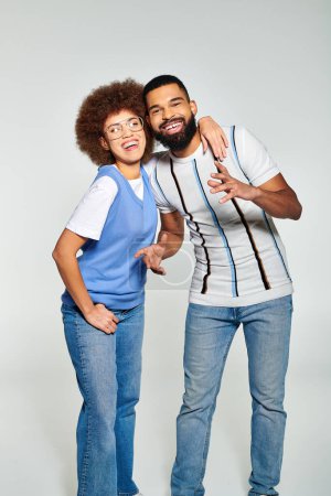 Foto de Un hombre y una mujer afroamericanos con ropa elegante posando para una foto con un fondo gris, mostrando su amistad. - Imagen libre de derechos