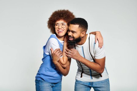 Foto de Una pareja afroamericana con ropa elegante comparte un cálido abrazo, expresando su profunda amistad contra un fondo gris. - Imagen libre de derechos