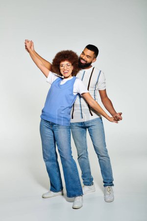 Photo for A man and a woman, dressed in stylish clothes, strike a pose together against a grey background as a symbol of friendship. - Royalty Free Image
