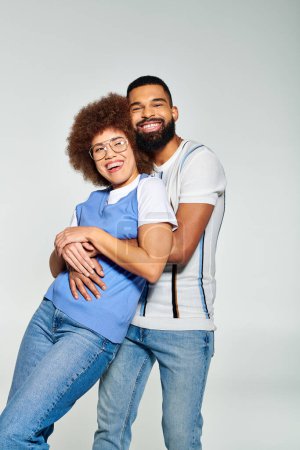 Foto de Un hombre y una mujer afroamericanos vestidos con estilo posan para una foto sobre un fondo gris, mostrando su amistad. - Imagen libre de derechos