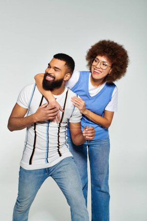 African American man and woman in stylish clothes, posing for a picture on grey background, showcasing their friendship.