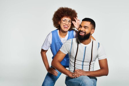Foto de Elegante hombre y mujer afroamericanos abrazan la amistad en una pose de moda sobre un fondo gris. - Imagen libre de derechos