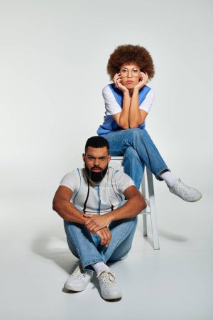 Téléchargez les photos : Amis afro-américains en vêtements élégants posent sur fond gris, mettant en valeur le lien entre un homme et une femme. - en image libre de droit