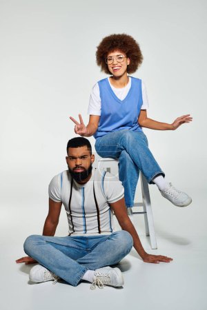 Foto de Un hombre y una mujer afroamericanos vestidos con estilo se sientan de cerca, mostrando amistad y camaradería. - Imagen libre de derechos