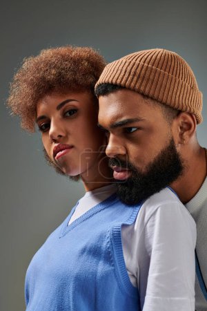 Photo for An African American man and woman, dressed in stylish clothes, strike a pose together against a grey background. - Royalty Free Image