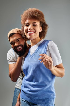 Foto de Un hombre y una mujer afroamericanos con ropa elegante riéndose juntos, mostrando su fuerte amistad sobre un fondo gris. - Imagen libre de derechos