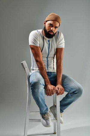 An African American man in stylish clothes sits atop a chair, showcasing relaxation