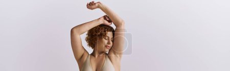 Téléchargez les photos : A young curvy redhead woman in a bikini flexes her arms. - en image libre de droit