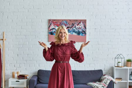 A mature woman in a vibrant red dress standing gracefully in a stylish living room.
