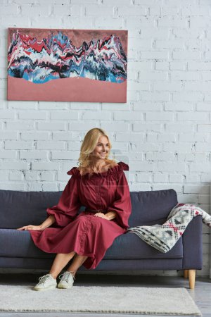 Stylish woman in red dress sitting on a couch.