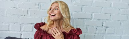 Photo for A mature woman in a red top is laughing joyfully. - Royalty Free Image