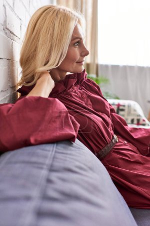 Photo for Stylish woman on couch in bright red dress. - Royalty Free Image