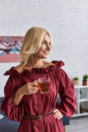 Mature lady in red dress enjoys a drink.