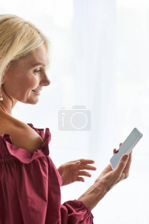 Femme élégante dans une robe rouge absorbée dans le téléphone.