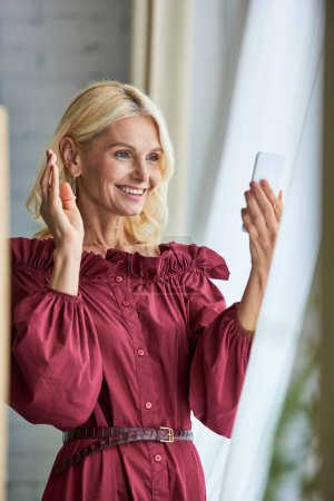 Stylish woman in elegant attire taking selfie with phone.