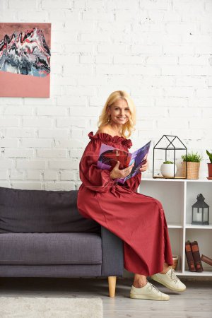 Mujer con estilo absorto en la revista en el sofá acogedor.
