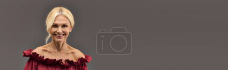 Foto de Una mujer madura y elegante en un vestido rojo chic emana confianza y luminosidad, sonriendo con gracia. - Imagen libre de derechos