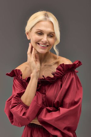 A mature elegant woman in a red chic dress strikes a pose.