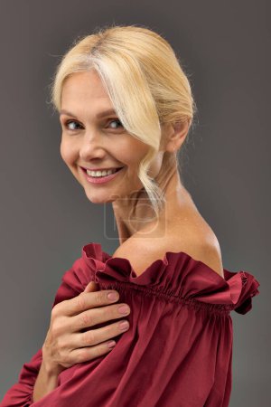 Elegant woman in red dress smiling at camera.