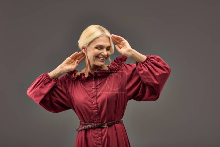 Photo for Mature woman in red dress posing with hands on her head. - Royalty Free Image