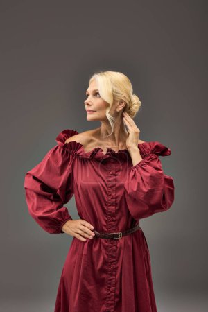 Eine reife, elegante Frau in einem roten Kleid, die in Pose tritt.