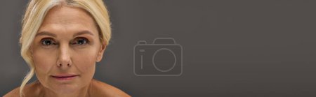 Foto de Atractiva mujer madura con el pelo rubio posando sobre fondo gris. - Imagen libre de derechos