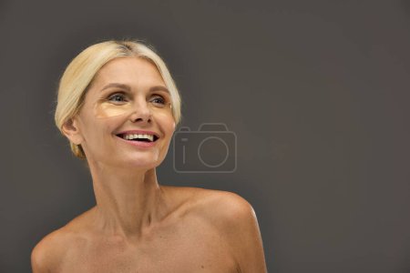 Photo for Appealing mature woman with blonde hair with eye patches on a gray backdrop. - Royalty Free Image
