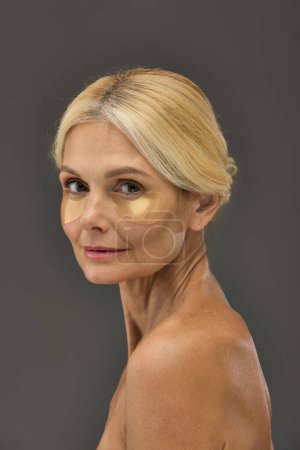Photo for Gorgeous mature woman with blonde hair with eye patches on a gray backdrop. - Royalty Free Image