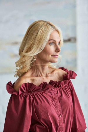 Photo for A mature woman with blonde hair in a stylish red blouse. - Royalty Free Image