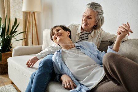 Deux femmes âgées assises sur un canapé, partageant un moment de compagnie et d'amour.