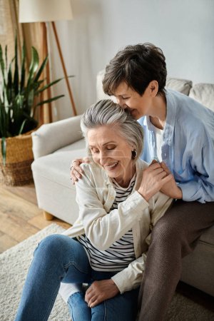Téléchargez les photos : A heartwarming moment as two elderly women hug each other on the couch. - en image libre de droit
