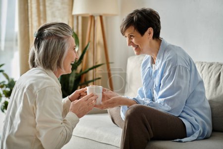 Photo for Two women, a loving mature lesbian couple, are sitting on a cozy couch and engaged in an intimate conversation. - Royalty Free Image