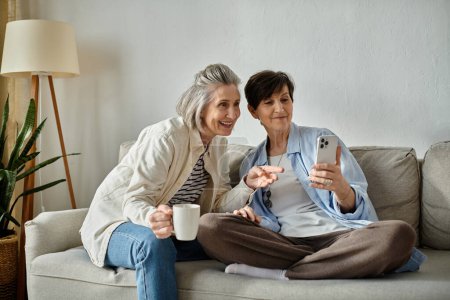 Foto de Dos ancianas en un sofá hipnotizadas por sus teléfonos. - Imagen libre de derechos