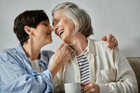 Dos mujeres mayores, una pareja lesbiana madura y cariñosa, comparten una taza de café en un acogedor sofá.