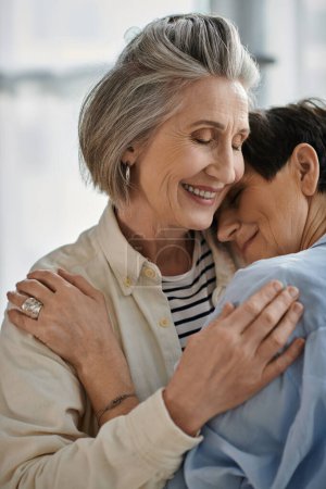 Dos mujeres mayores con expresiones amorosas abrazándose tiernamente.
