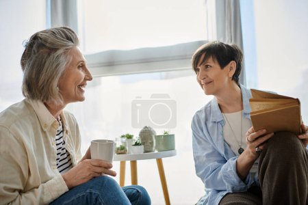 Dos mujeres mayores entablando una animada conversación en un sofá.