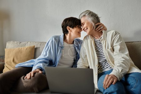 Téléchargez les photos : Deux femmes âgées assises sur un canapé, utilisant un ordinateur portable. - en image libre de droit